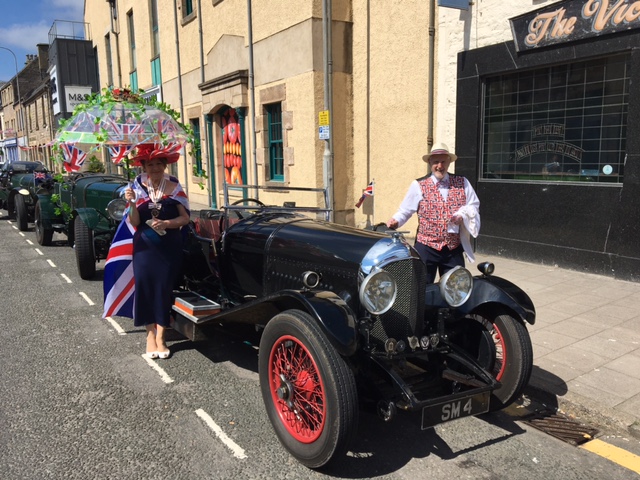 Deputy Lieutenant Joan and John Cowe dressed for the Jubilee and stand with Lord Lieutenant's Bentley on Elgin High Street